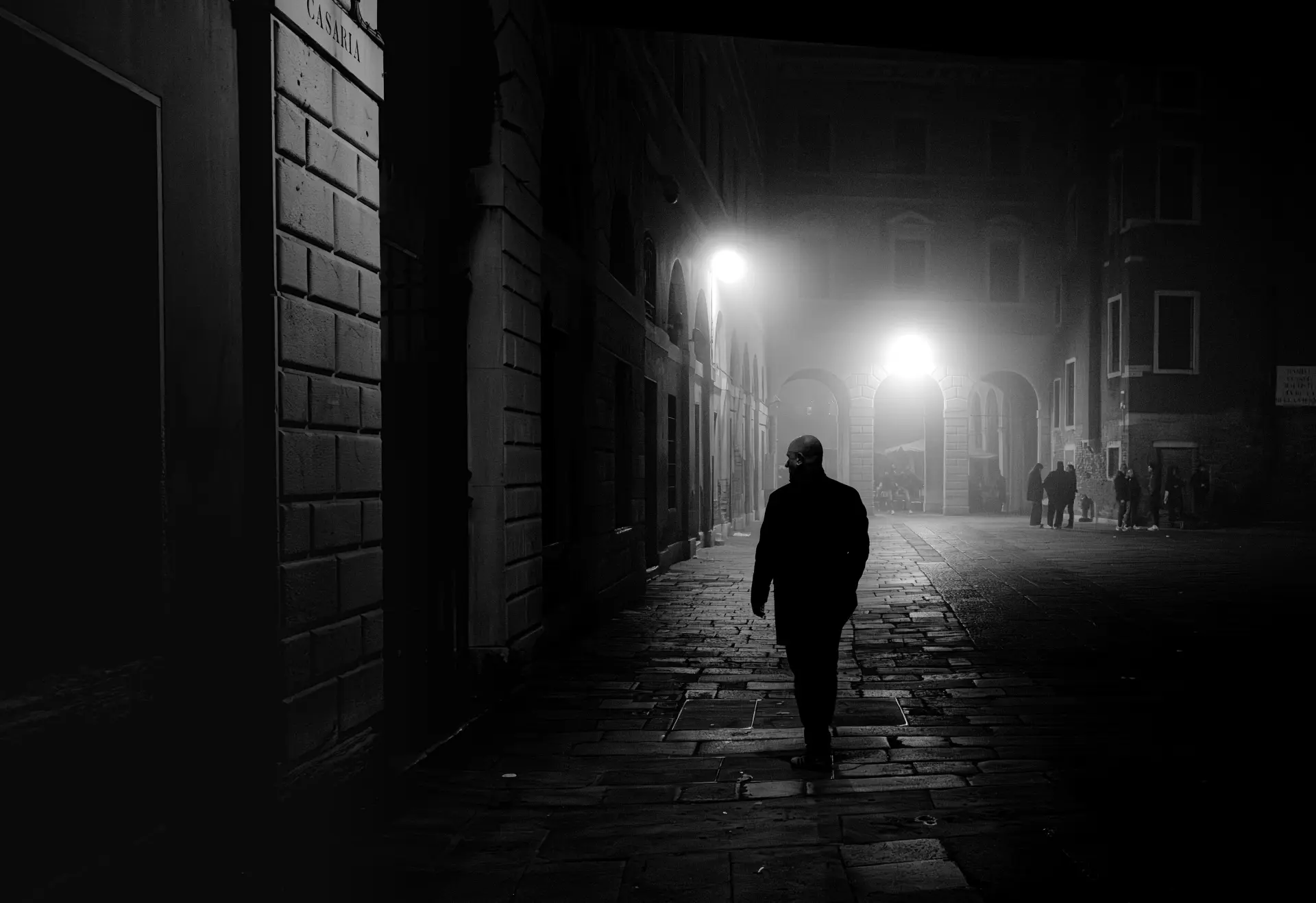 Nächtliche, minimalistische Straßenaufnahme mit einzelner Silhouette und diffusem Licht von Urs Renggli, die Ruhe und meditative Ordnung vermittelt