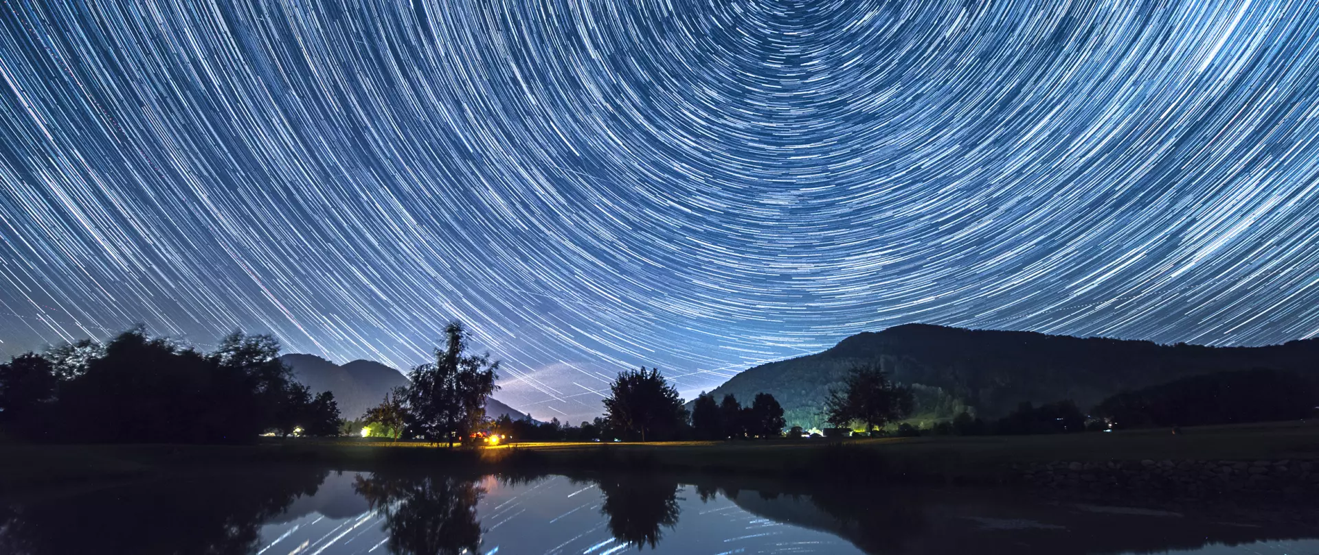Langzeitbelichtung des Sternenhimmels mit kreisförmigen Sternenspuren über einer Gebirgslandschaft – Astrofotografie von artistravel Dozent Hartmut Pönitz