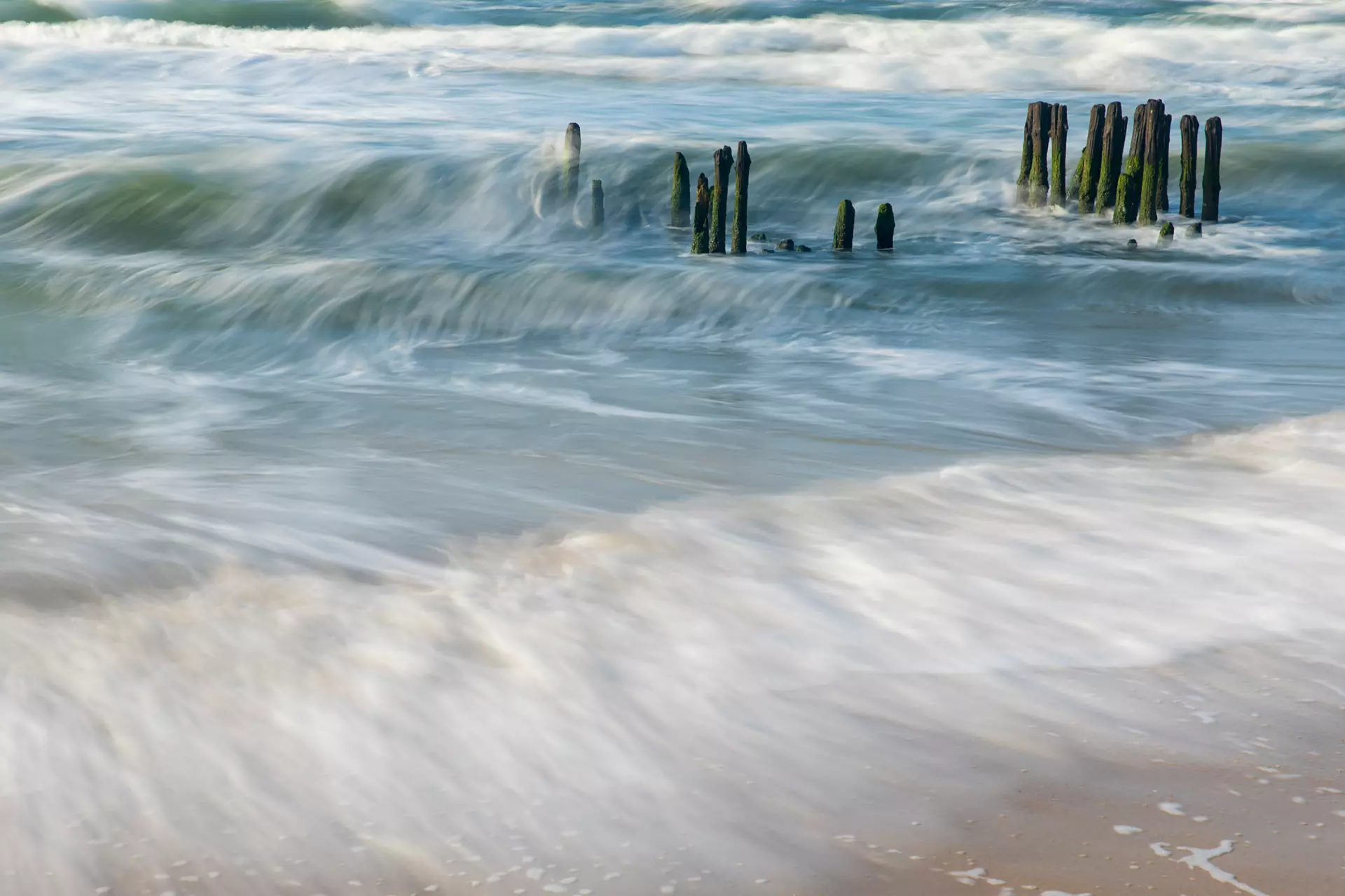 Meer mit Holzpfählen mit fließendem Wasser Bewegte Nordseewellen treffen auf alte Holzpfähle – stimmungsvolle Aufnahme von artistravel Fotografie Dozentin Marion Hogl