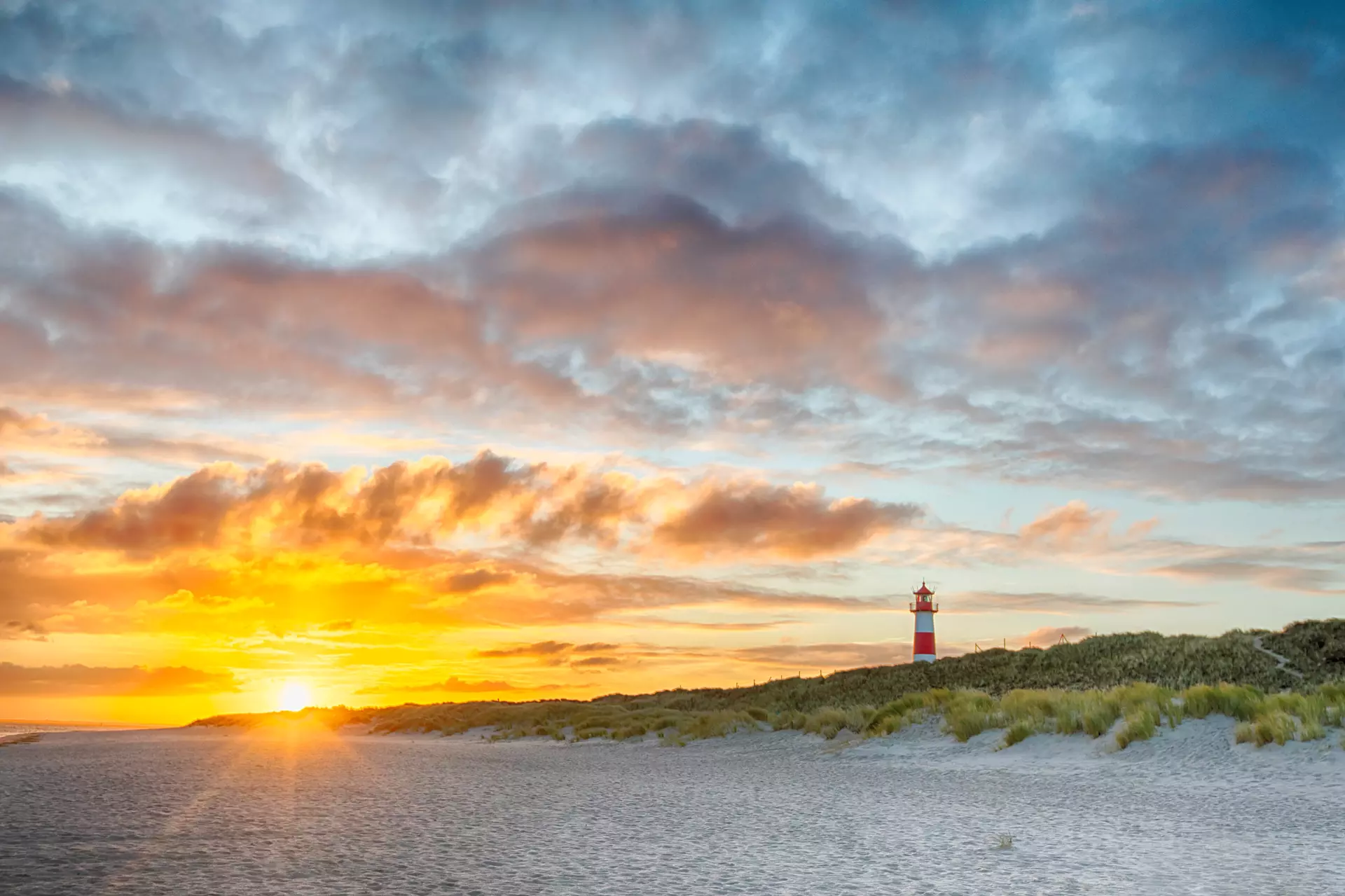 Leuchtturm im Abendlicht Leuchtturm in Dünenlandschaft vor farbenprächtigem Himmel – Naturfotografie von artistravel Dozentin Marion Hogl