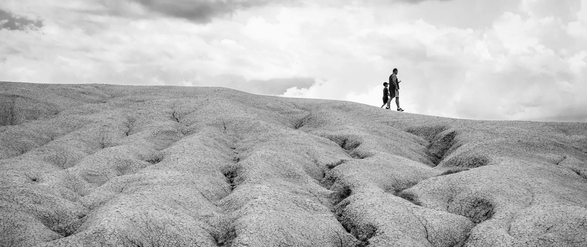 Schwarz-weiß Fotografie einer surrealen Landschaft mit Mensch in weiter Ferne – artistravel Dozent Ron Kuhwede