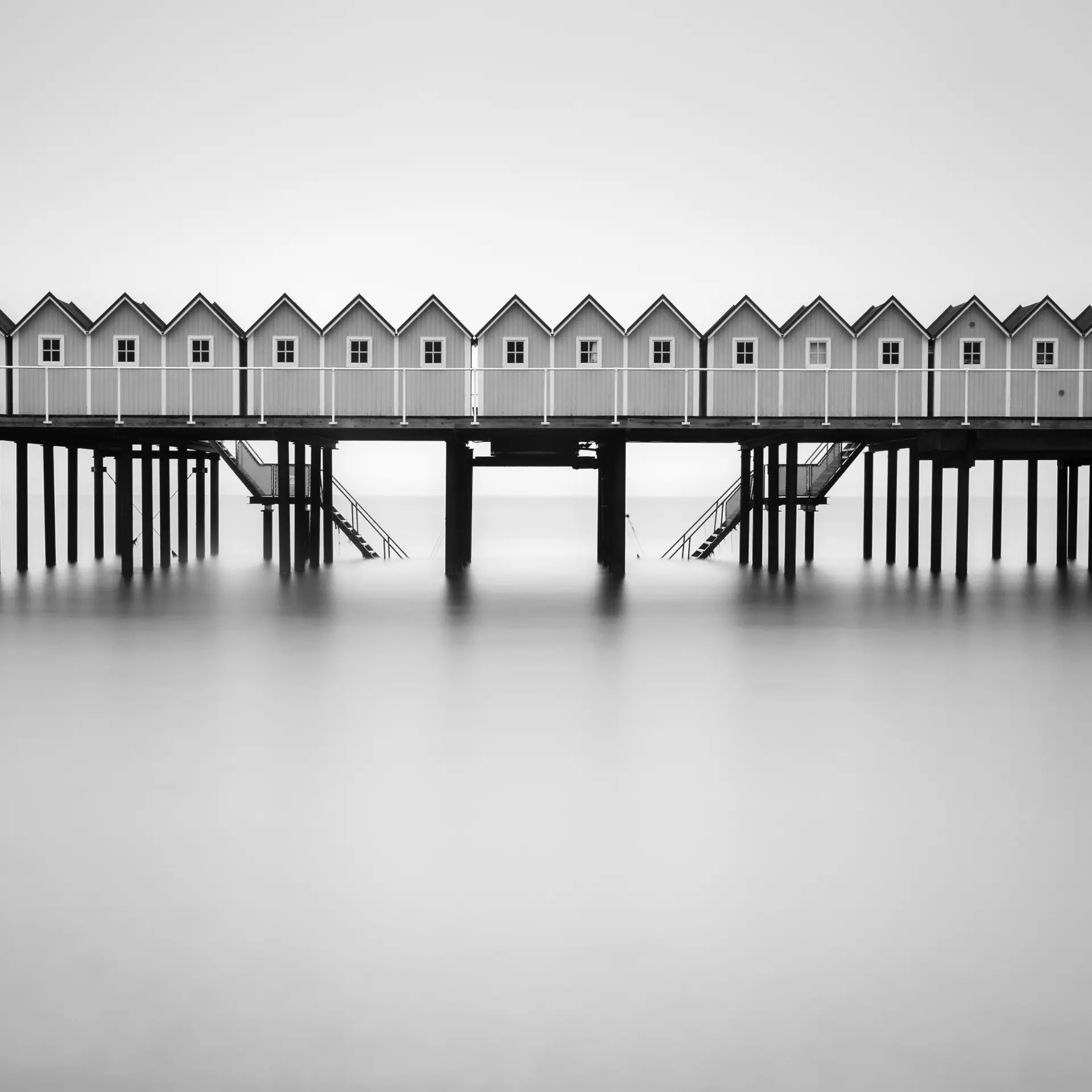 Schwarz-Weiß Landschaftsfotografie mit grafischen Strukturen Schwarz-weiß Fotografie von Badehäuschen auf einem Steg – minimalistische Komposition von artistravel Dozent Thomas Bichler