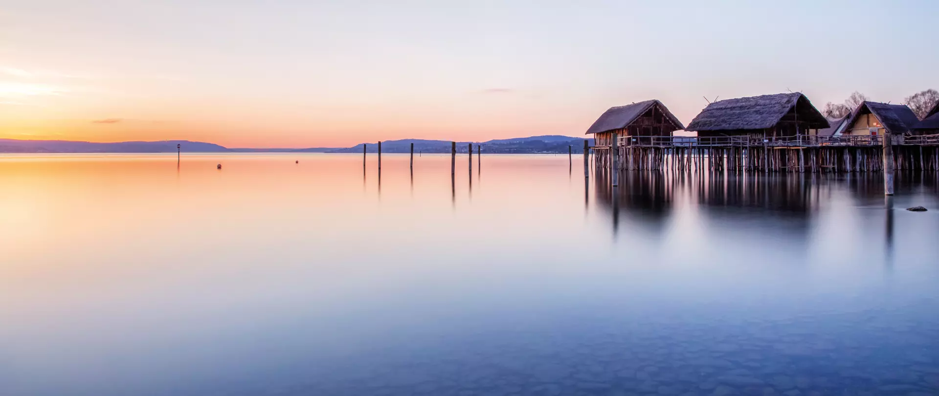 Idyllische Uferlandschaft mit Pfahlbauten bei Sonnenuntergang – Landschaftsfotografie von artistravel Dozent Thomas Bichler