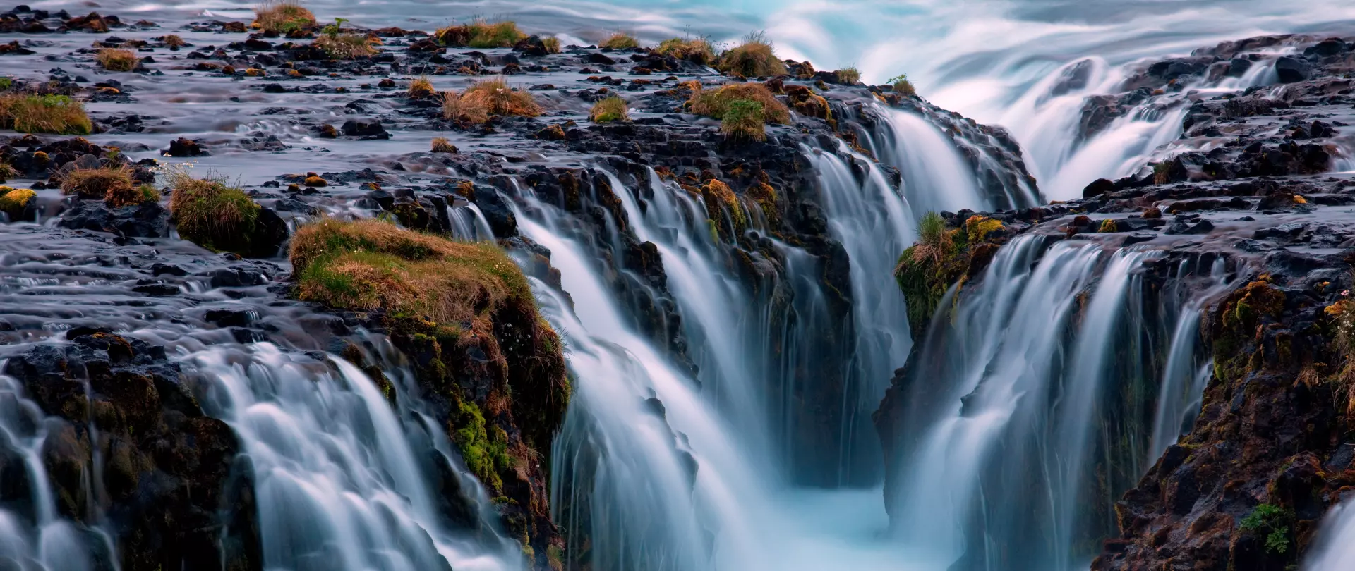 Reißender Wasserfall in einer felsigen Landschaft mit kargen Pflanzen – Landschaftsfotografie von artistravel Dozent Uwe Schmid