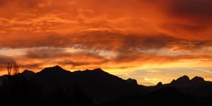 Die Fotografie zeigt Gebirge und im Hintergrund geht die Sonne unter.