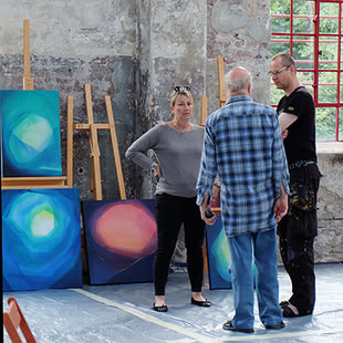 Ein Kursbild, das drei Personen zusammenstehend in einem Atelier abbildet.