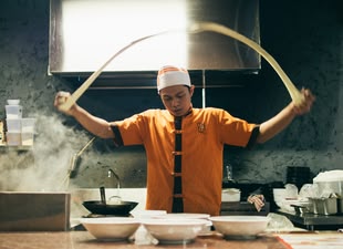 Food-Shots inszenieren lernen im Fotokurs: Reisefotografie. Foto: Aditya Romansa/Unsplash. Das Foto stellt einen Koch in einer Küche da.