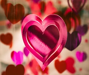 Schreiben lernen - Creative Writing/Kreatives Schreiben; Romance. Foto: Clem Onojeghuo/Unsplash Ein gebasteltes Herz aus glänzendem pinken Papier hängt an einem Faden