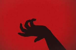 Schreiben lernen - Creative Writing/Kreatives Schreiben; Crime Fiction/Krimi. Foto: Romain MATHON/ Unsplash Der Schatten einer verkrampften Hand vor einer roten Wand