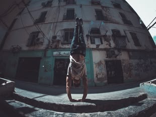 Fotografie eines Mannes, der einen Handstand auf der Straße macht.