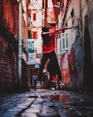 Farben in der Fotografie einsetzen lernen im Fotokurs. Foto: safal karki/Unsplash. Die Fotografie zeigt einen Mann in einer Straße, der in die Luft springt.