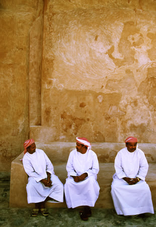Fotografieren lernen im Fotokurs - Reisefotografie. Foto: Björn Göttlicher. Eine Fotografie von Björn Göttlicher, die drei Männer sitzend vor einem Gebäude abbildet.