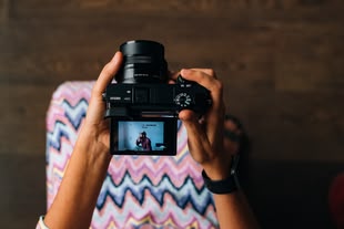 Eine Person guckt sich auf einer Kamera ein zuvor geschossenes Foto an.