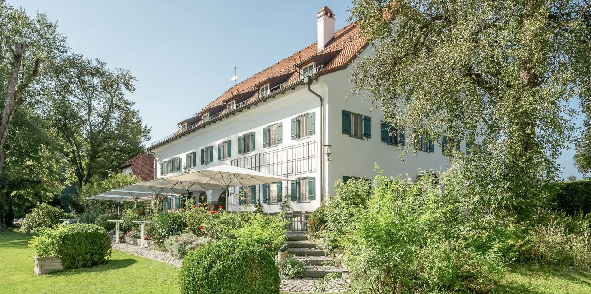 Foto von einem großen weißen Haus auf einer grünen Wiese mit vielen Fenstern (das Hotel Aiterbach)