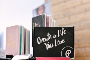 Bullet Journal gestalten - Self Care / Tracker / Logs / Malen und Zeichnen lernen. Foto: Allie Smith/Unsplash Ein Notizbuch mit der Aufschrift "Create a Life You Love" steht vor anderen Notizbüchern
