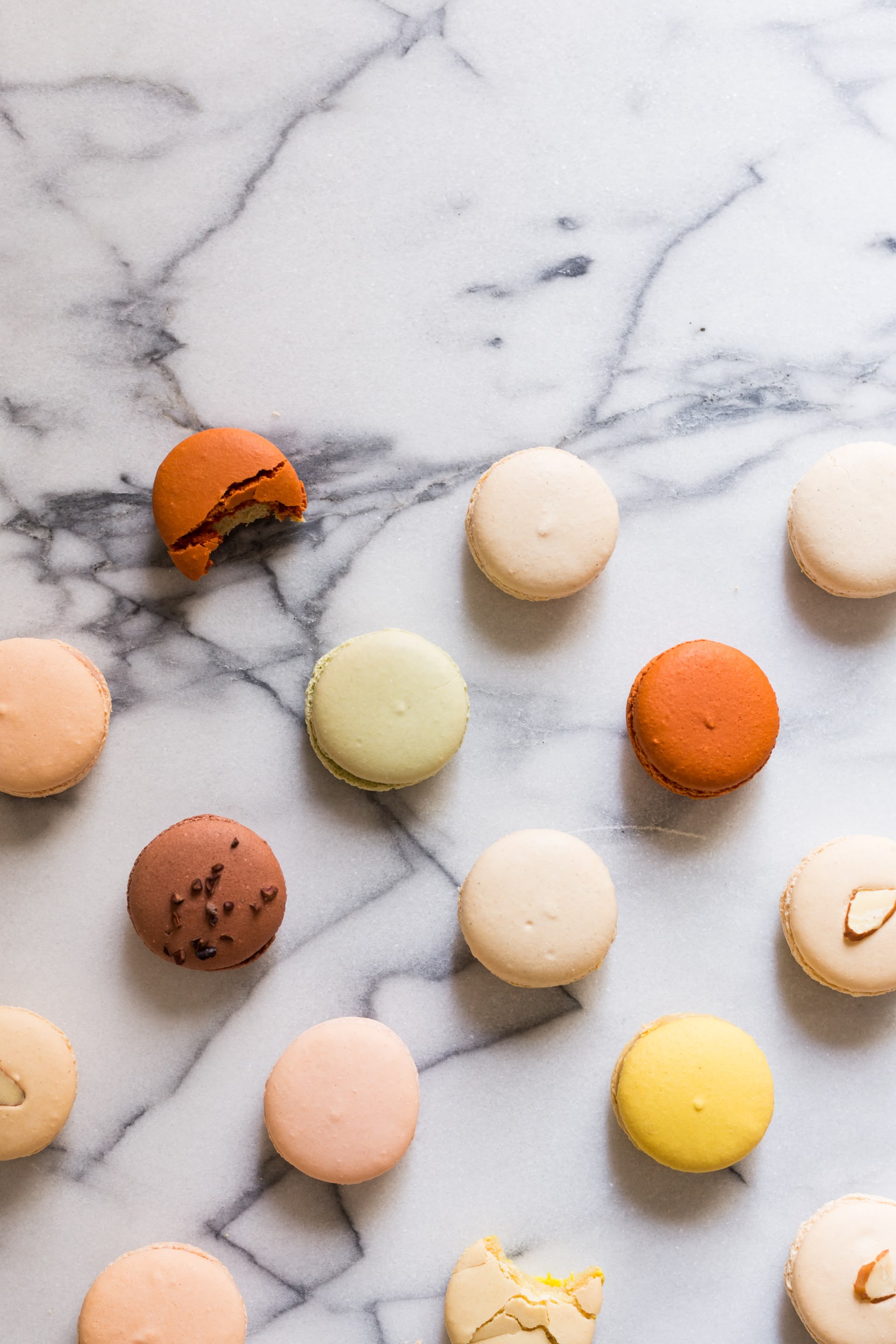 Auf einer Marmor-oberfläche liegen mehrere Macarons.