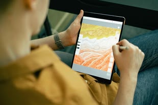 Ein junger Mann sketcht auf einem iPad