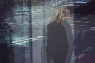 Fotografieren lernen im Fotokurs. Foto: Sunyu/Unsplash. Fotografie durch eine Glasscheibe hindurch. Es ist eine Fußgängerin auf einer Straße zu sehen.