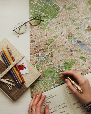 Gute Reisefotos durch gute Planung! Fotografieren lernen im Fotokurs. Foto: oxana v/Unsplash. Auf einer Stadtkarte liegen verschiedene Objekte.