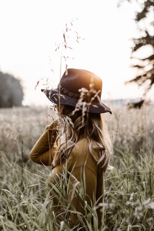 Fotografieren lernen im Fotokurs: Nah rangehen statt zoomen! Foto: Priscilla Du Preez/Unsplash. Eine Frau mit einem Hut steht in einem Feld.