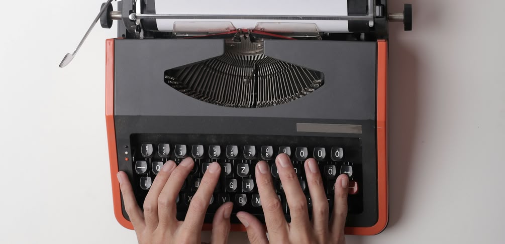 2 Hände auf der Tastatur einer mechanischen Schreibmaschine