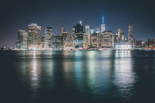 Bearbeitung mit der HDR-Technik ermöglicht es, die hell erleuchteten Gebäude und das dunkle Wasser ohne Kompromiss gleichzeitig abzubilden. Foto: Jan Senderek/Unsplash. Fotografie einer Skyline am Wasser bei Nacht.