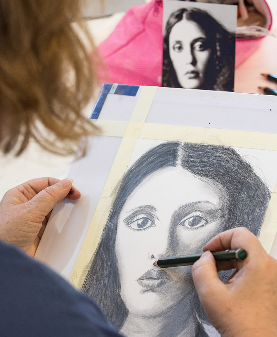 Blick über die Schulter einer Frau, die an einer Portraitzeichnung arbeitet