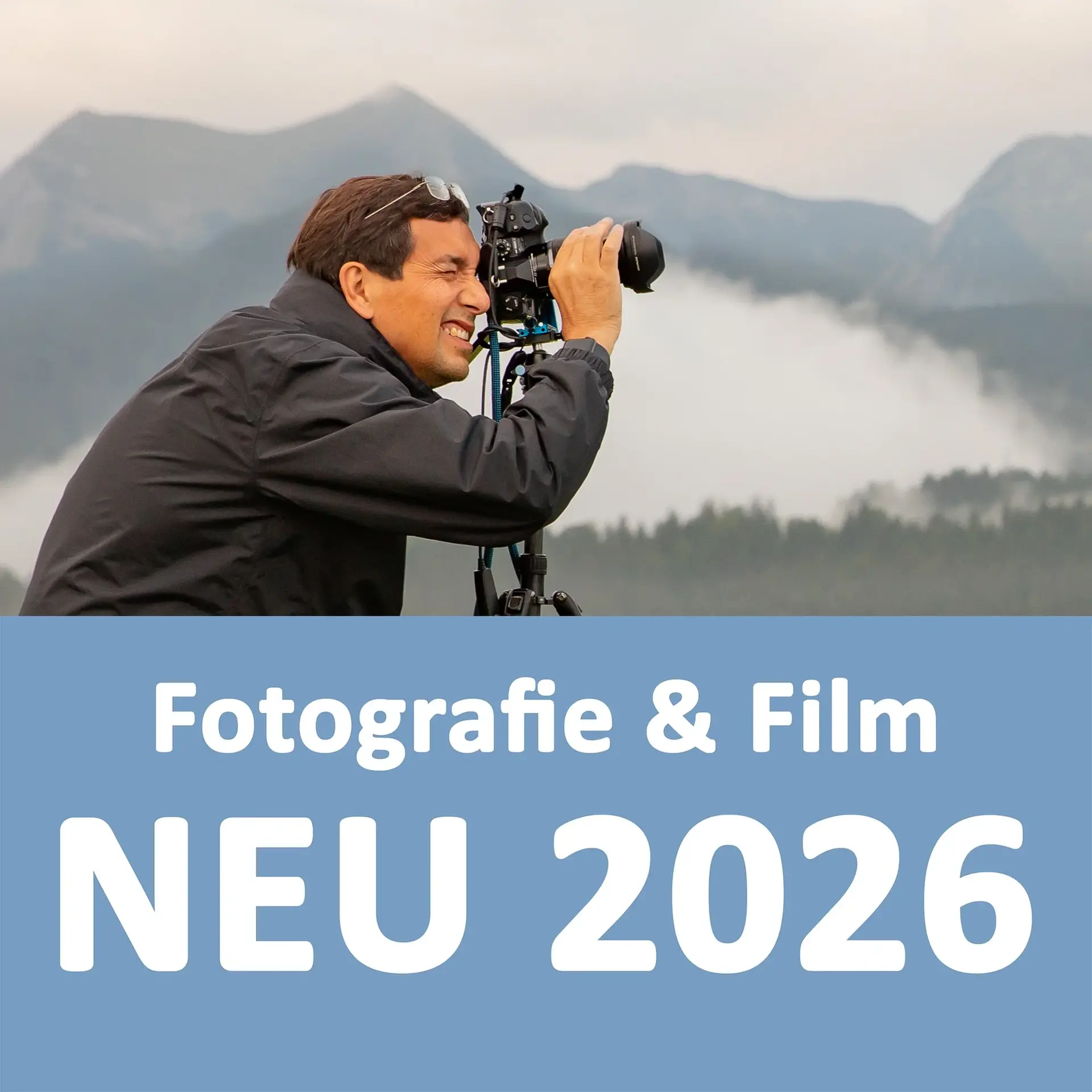 Ein Mann blickt durch den Sucher einer Kamera, die draußen in den Bergen auf einem Stativ steht 