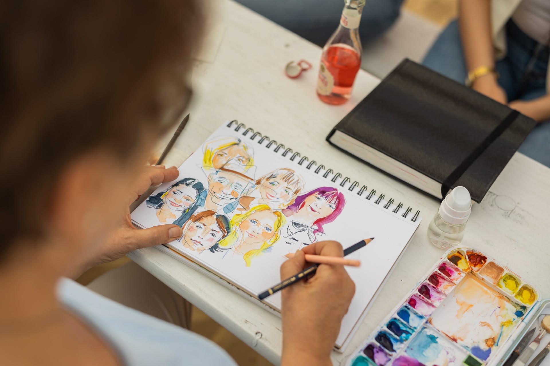 Blick über die Schulter einer Frau (Dozentin Ulrike Selders), die gerade ihr Gegenüber sketcht