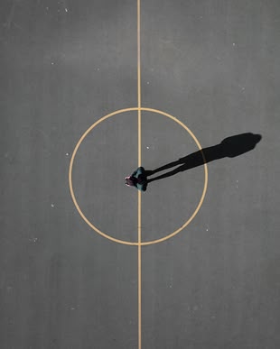 Fotografieren lernen im Fotokurs: Bildgestaltung. Foto: Luís Eusébio/Unsplash. Eine Person steht in der Mitte eines Spielfeldes.