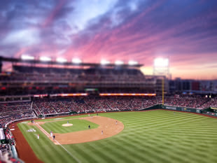 Schärfeeffekt mit Tilt und Shift - Fotografieren lernen im Fotokurs. Foto: "nats-game-tilt-shift" by Ryan McKnight (CC BY 2.0 - https://creativecommons.org/licenses/by/2.0/). Ein Football-Feld fotografiert während eines Sonnenunterganges.
