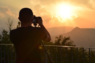 Foto: Nico Cavallini on Unsplash Ein Mann richtet seine Kamera auf die vor ihm liegende Landschaft.