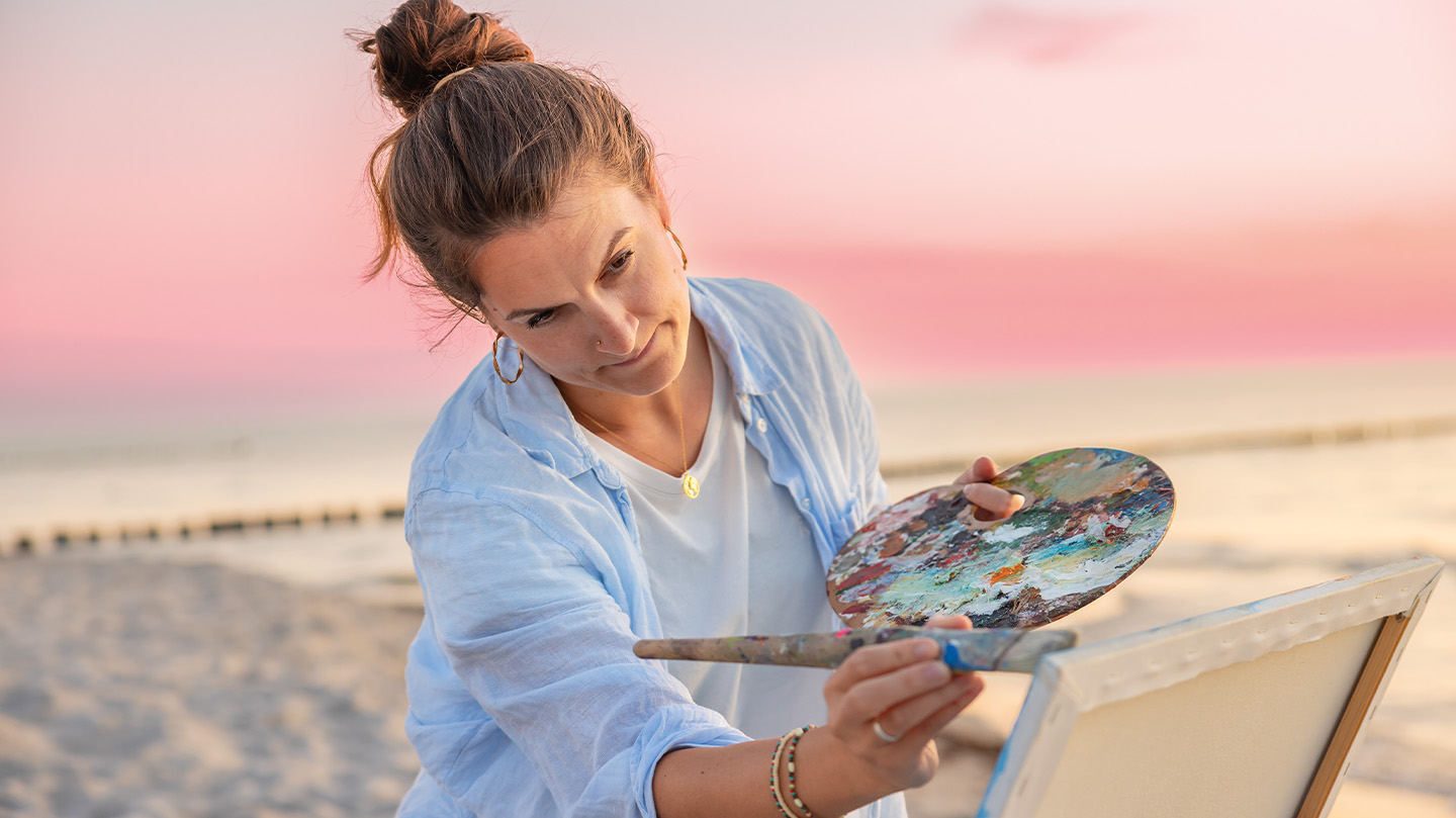 Malerin bei Sonnenuntergang am Strand